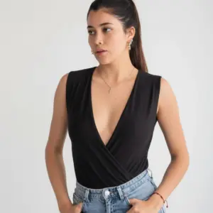 Body Chloe cruzado sin mangas negro con escote en V profundo, combinado con jeans de mezclilla claros.