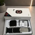 Smartwatch T500 Ultra plateado en caja blanca, incluye pantalla cuadrada, correa de silicona negra con hebilla y manual de usuario.