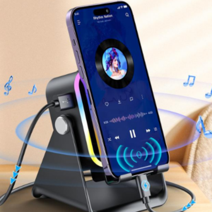 Soporte altavoz inalámbrico negro con luces RGB y carga por inducción sosteniendo un smartphone en un escritorio.