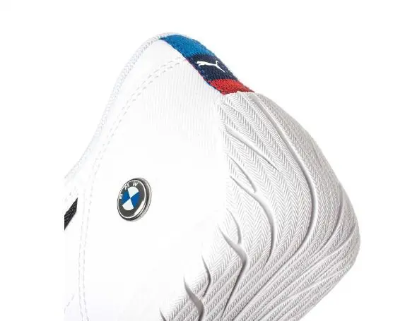 Tenis Puma BMW Motorsport blancos de perfil bajo con suela texturizada, emblema metálico en el lateral y detalle tricolor en el talón.