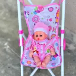 Coche de juguete plegable en metal blanco con asiento de tela estampada rosa y muñeca con gorro y ropa a rayas.