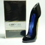 Perfume de mujer en frasco con forma de tacón alto azul oscuro brillante y estuche cuadrado en blanco y negro con detalles dorados.