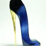 Perfume femenino en envase de vidrio azul oscuro con forma de zapato de tacón aguja dorado brillante y parte superior negra.