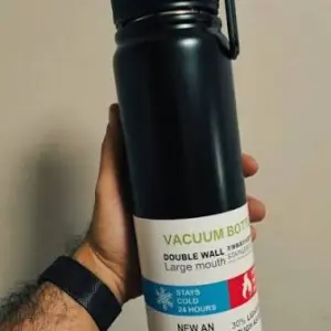 Termo deportivo negro de acero inoxidable con tapa de rosca y asa, etiqueta frontal que destaca aislamiento al vacío para bebidas frías por 24 horas.
