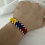 Manilla doble de neopreno con cuentas mate en amarillo, azul y rojo, con separadores de oro de 18k, lucida en la muñeca.