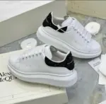 Zapatos Alexander McQueen de cuero blanco con suela gruesa y talón negro brillante con purpurina, en caja con repuestos.