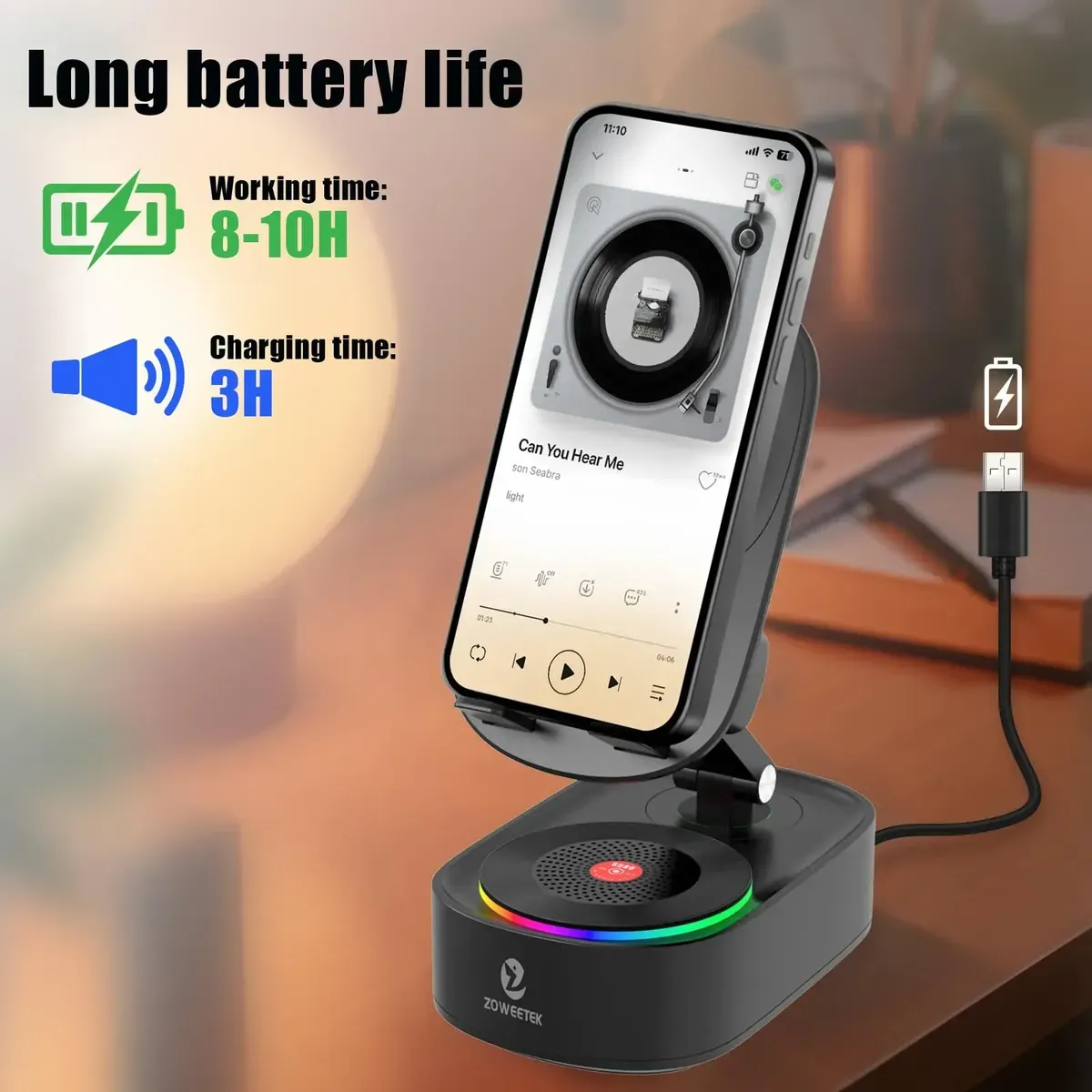 Soporte negro y base con parlante inalámbrico circular, luces LED de colores y celular instalado, conectado a un cable USB sobre escritorio de madera.