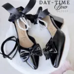 Par de zapatos de tacón en bloque negros de charol, con lazo frontal, perlas y cinta satinada.