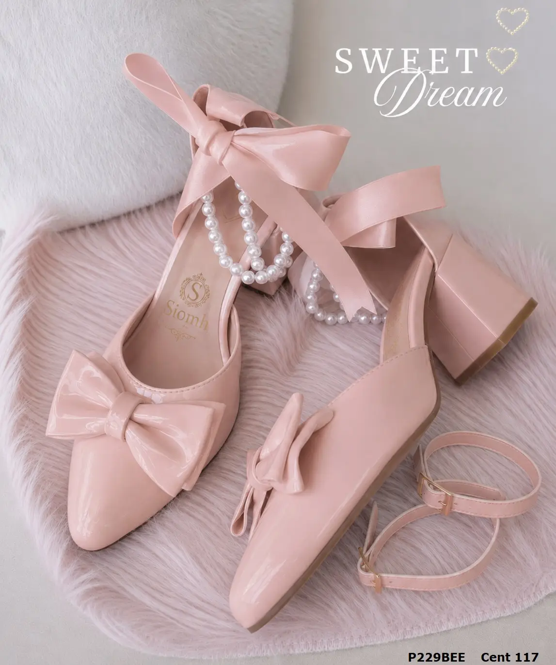 Zapatos de tacón en bloque color rosa claro, acabado brillante, con lazos decorativos en la punta y perlas colgantes en el tobillo.