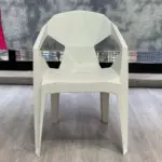 Silla moderna de polipropileno blanco con diseño geométrico de facetas tipo diamante, brazos integrados y patas angulares sobre piso de madera.