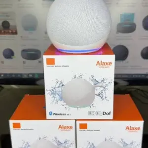 Parlante portátil Bluetooth esférico blanco con base iluminada en LED azul, ubicado sobre tres cajas empacadas del mismo modelo.
