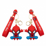 Dos llaveros de silicona de Spider-Man con figura grande sentada en rojo y azul, correa roja con texto y argolla dorada para mochilas.