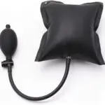 Cuña inflable de aire negra con bomba de mano de goma y manguera, ideal para nivelar puertas y muebles pesados.