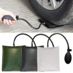 Cuña inflable de aire negra soportando el peso de una llanta de carro, con pera de inflado manual y manguera. Abajo se muestran tres versiones en colores verde, negro y gris claro.