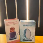 Empaques de rodillo facial de silicona con pétalos de rosa y depilador de nanocristal en tonos rosa y azul sobre superficie amarilla.
