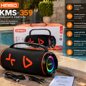 Parlante portátil bluetooth negro con luces LED RGB en los laterales, acompañado de su caja, cable de carga, cable auxiliar y manual en el borde de una piscina.