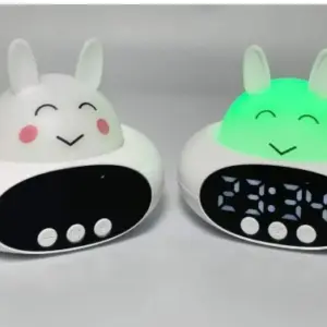 Dos relojes despertadores infantiles con diseño de conejito blanco y base ovalada; uno apagado y otro con luz LED verde encendida y pantalla digital activa.