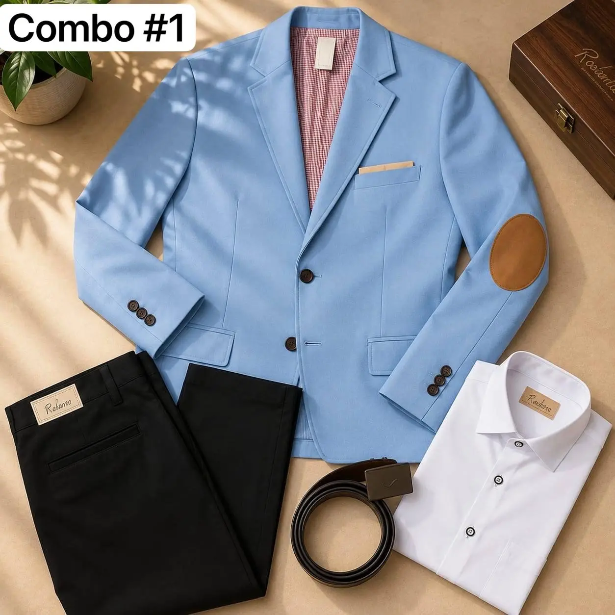 Conjunto formal infantil azul claro: blazer con codera marrón, camisa blanca, pantalón negro y correa sobre superficie de madera.