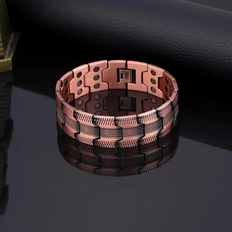 Pulsera de cobre color oro rosa con eslabones texturizados y pequeños imanes negros en su interior, sobre una superficie oscura reflectante.