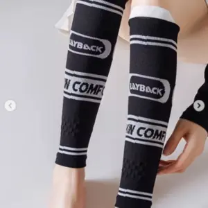 Pantorrilleras de compresión negras con rayas, texto blanco y textura acanalada, ajustadas a las piernas para entrenamiento deportivo.