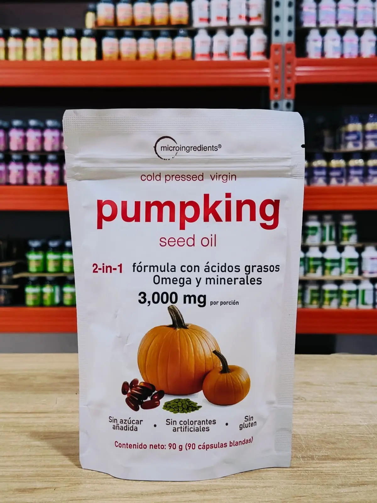 Bolsa blanca de aceite de semilla de calabaza microingredients, 90 cápsulas blandas de 3,000 mg, con de calabazas sobre mesa de madera.