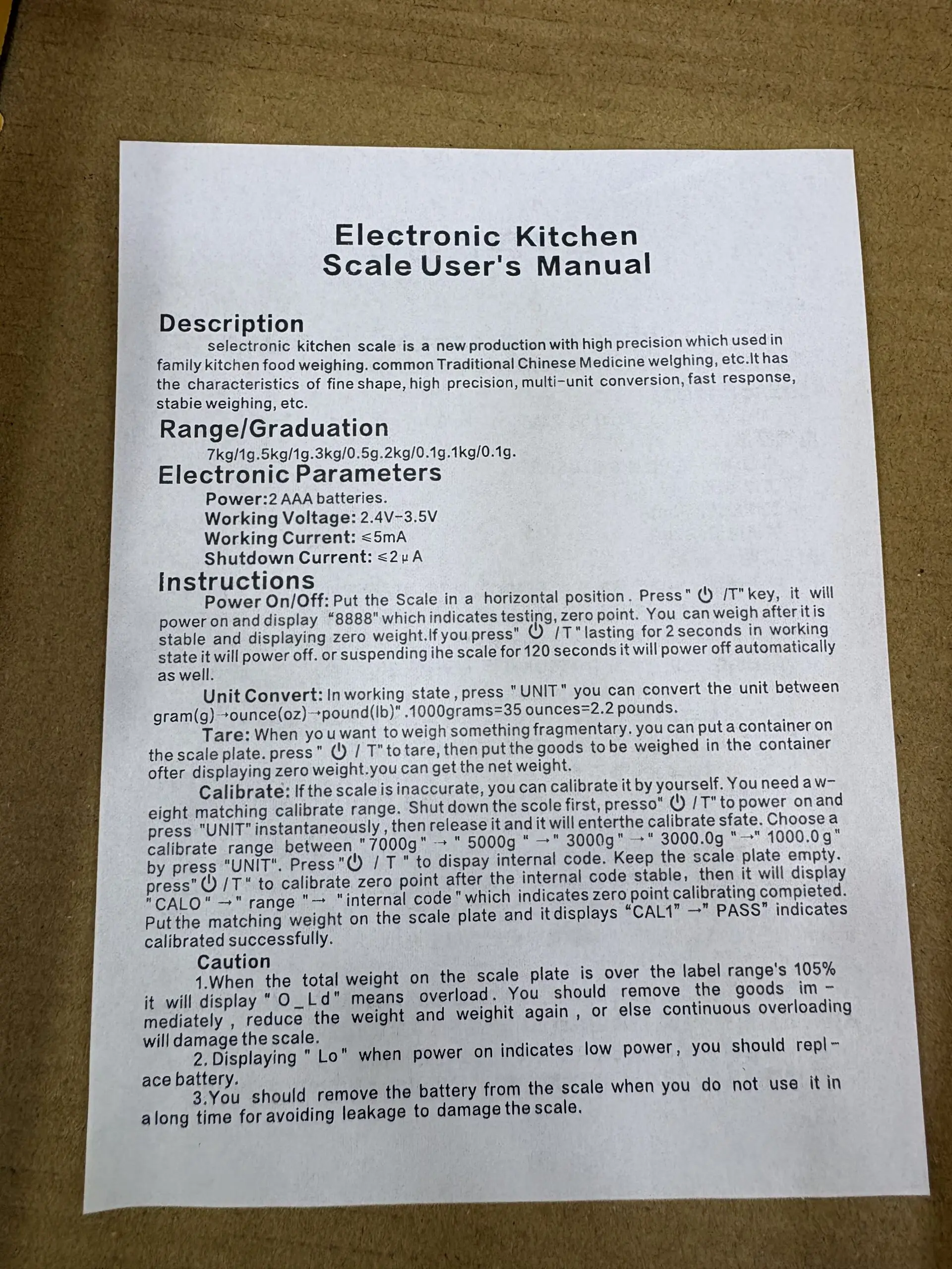 Manual de usuario para báscula de cocina digital, impreso en papel blanco sobre superficie de cartón.