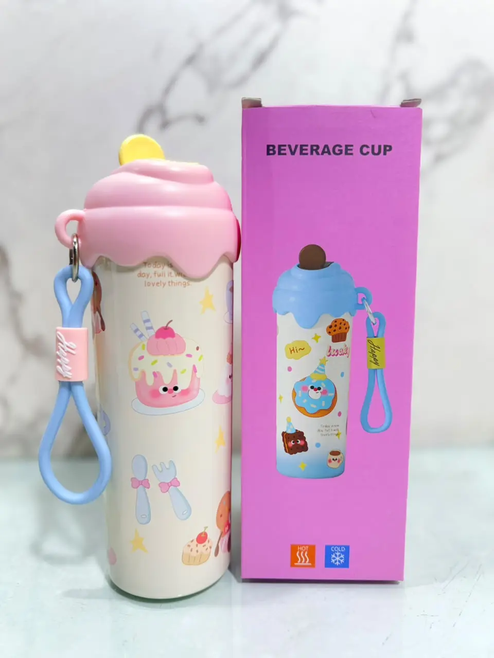 Termo kawaii blanco de 600ml con diseño de pastelitos, tapa rosa en relieve, correa azul y su caja de empaque rosa.
