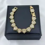 Pulsera dorada con dijes de corazones cristalinos pavé dispuesta sobre estuche negro cuadrado para regalo elegante.
