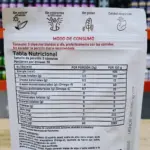 Tabla nutricional y modo de uso en bolsa blanca de suplemento con cápsulas, indicando porción de 3 unidades y 30 porciones por envase.