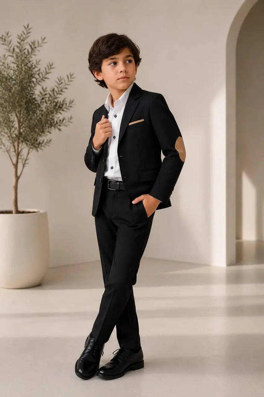 Traje formal infantil negro con blazer de coderas camel, camisa blanca, pantalón slim, correa negra y zapatos formales.