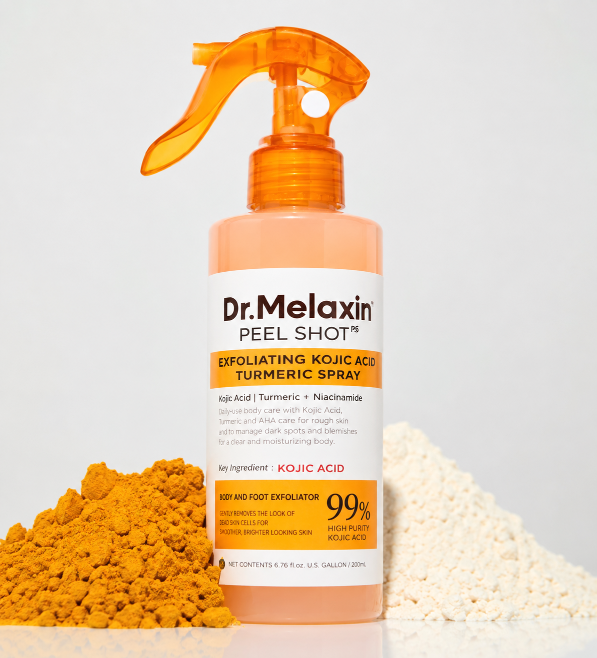 Spray exfoliante corporal naranja con ácido kójico y cúrcuma, flanqueado por montículos de polvos amarillo y blanco sobre superficie blanca.