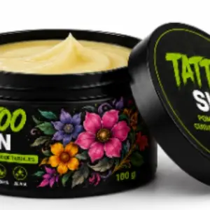 Tarro negro de 100 g de pomada Tattoo Skin con crema de textura suave color crema, envase con diseño floral y tapa apoyada al lado.