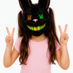 Niña usando máscara de conejo LED negra con orejas peludas, ojos cruzados luminosos verde y naranja, y sonrisa brillante para fiestas.