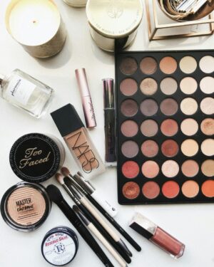 Paleta de sombras y productos de maquillaje sobre una mesa