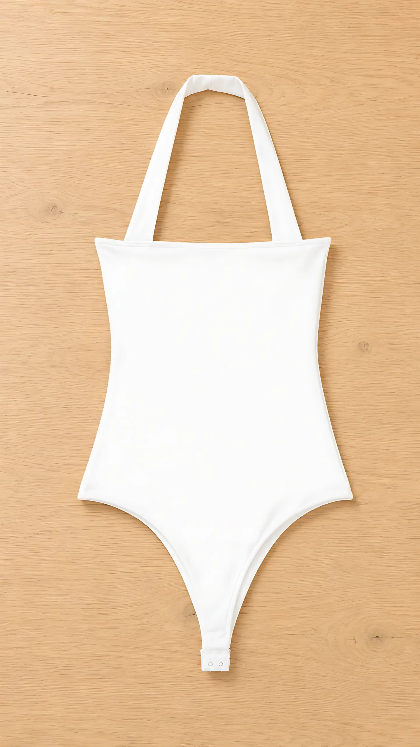 Body blanco de cuello halter y corte de pierna alta, extendido sobre un fondo de madera clara.