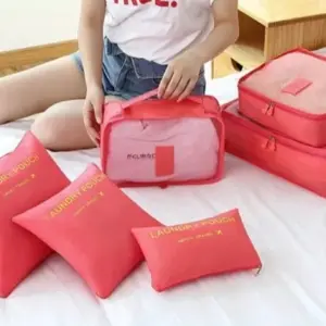 Set de seis organizadores de viaje salmón impermeables sobre una cama, con tres cubos de malla translúcida y tres bolsas para lavandería.