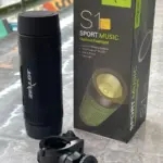 Parlante Bluetooth Zealot S1 negro cilíndrico, caja de empaque verde y negra y soporte de montaje sobre superficie de mármol.