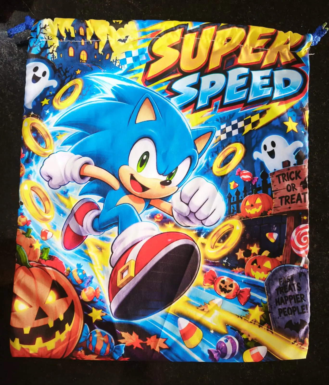 Bolsa de tela con cordón para dulces con diseño de Sonic el Erizo, calabazas, fantasmas y anillos dorados en colores azul y naranja vibrantes.