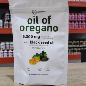 Bolsa blanca de aceite de orégano con semilla negra, 6,000 mg de equivalente herbal, con diseño de hojas y gotas sobre mesa de madera.