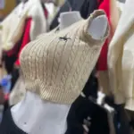 Top tejido sin mangas color café con textura de trenzas, cuello en V y pequeño logo frontal, exhibido en maniquí blanco.