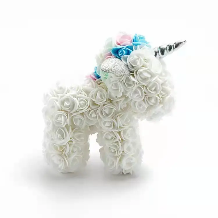 Unicornio de rosas eternas blancas con crin de rosas azules y rosadas, cuerno plateado y oreja con brillo, visto de perfil.