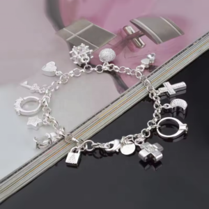 Pulsera de eslabones plateada con baño de rodio y múltiples dijes colgantes variados sobre superficie brillante.