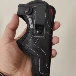 Funda negra texturizada de cuero ecológico para pistola, sostenida en una mano con gancho metálico y costuras blancas visibles.