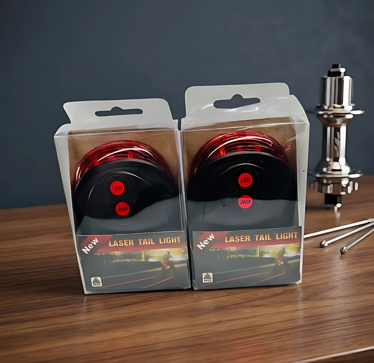 Dos cajas de luz trasera LED y láser para bicicleta en empaque transparente, dispuestas sobre una superficie de madera.