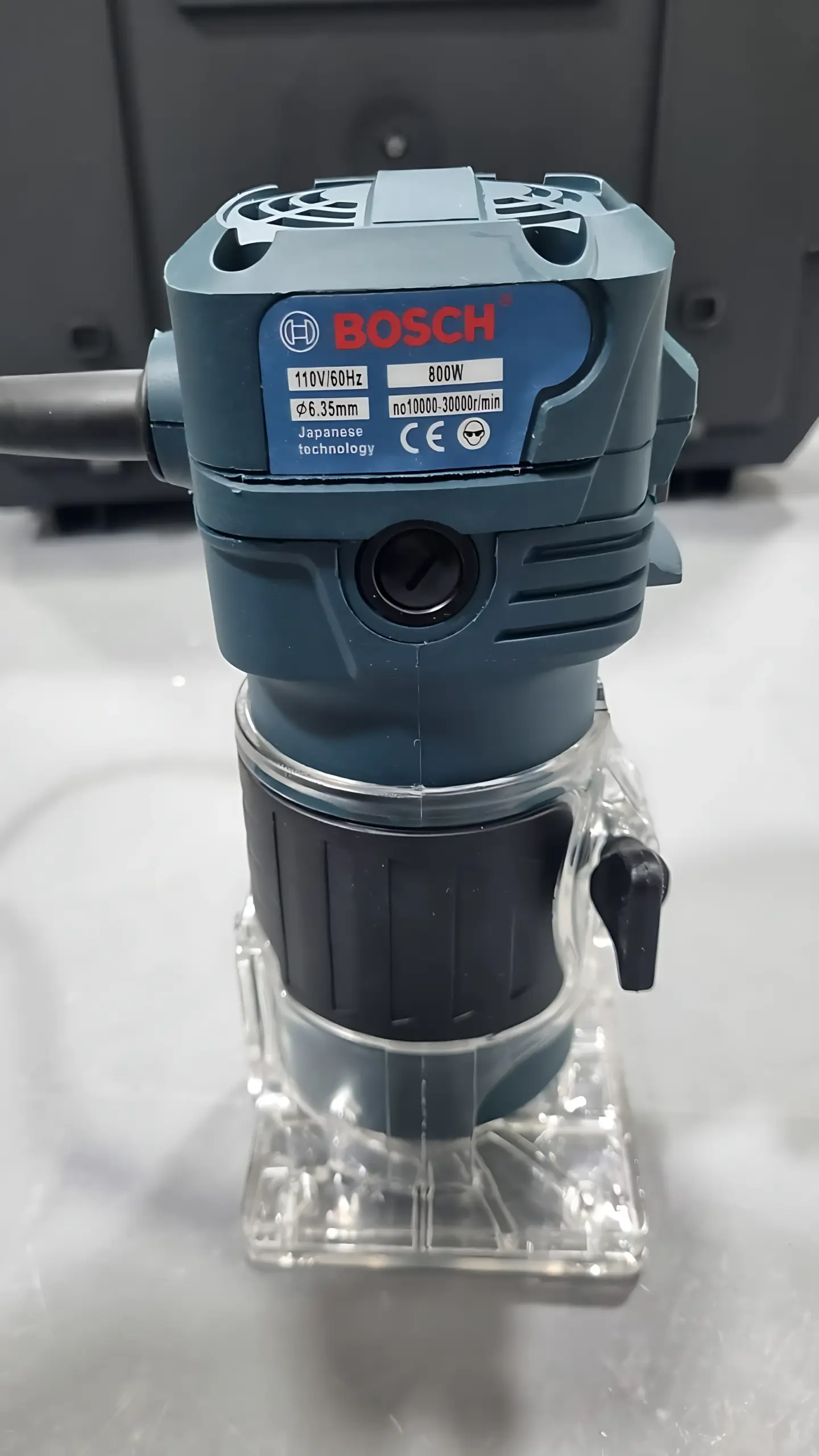 Rebordeadora eléctrica azul y negra de 800W con base transparente de acrílico y cable de alimentación.