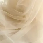 Textura de tul color crema con pliegues suaves y delicados de un toldillo circular para cama king, material ligero y translúcido.
