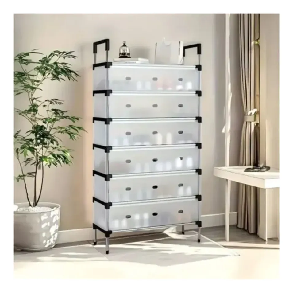 Zapatera organizadora gris de 6 niveles con tapas translúcidas para calzado, ubicada en sala con planta decorativa y escritorio.