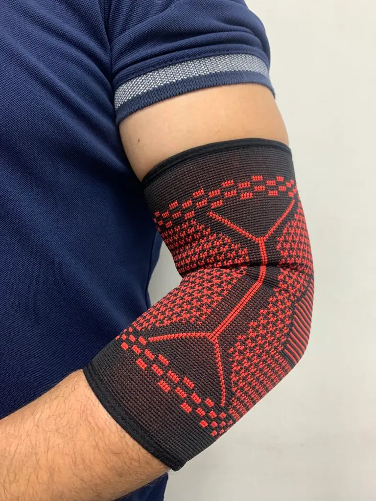 Codera elástica negra con diseño geométrico en rojo, ajustada al codo para brindar soporte y compresión durante el entrenamiento.