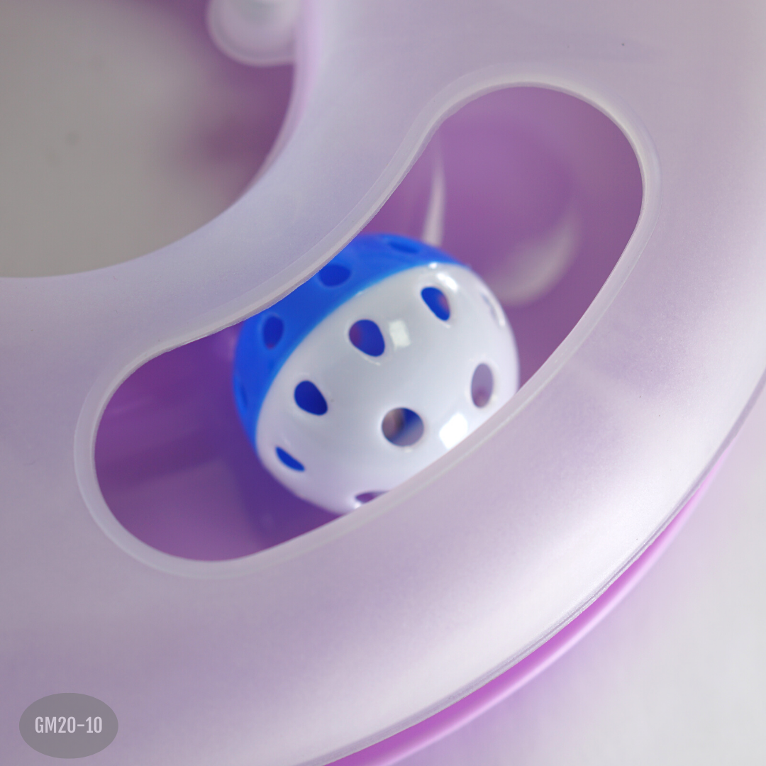 Primer plano de pelota perforada azul y blanca en la pista circular morada de un juguete interactivo para gatos.
