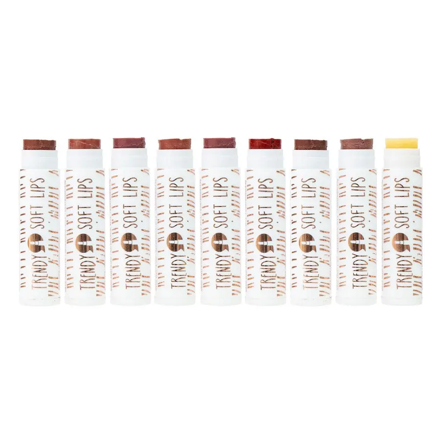 Nueve bálsamos labiales Trendy Soft Lips alineados, con envases blancos y diversos tonos de color, desde café y terracota hasta rojo y nude.